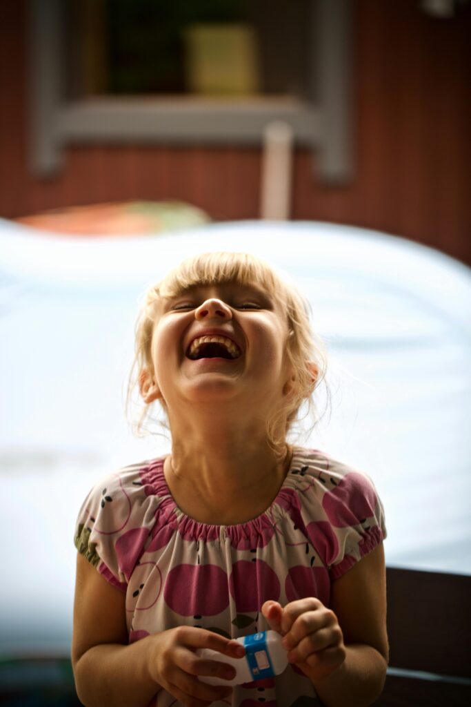 A young girl bursts into laughter, capturing the essence of childhood joy and innocence.