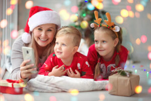 Glückliche Familie schaut sich eine Videobotschaft vom Weihnachtsmann auf dem Handy an.